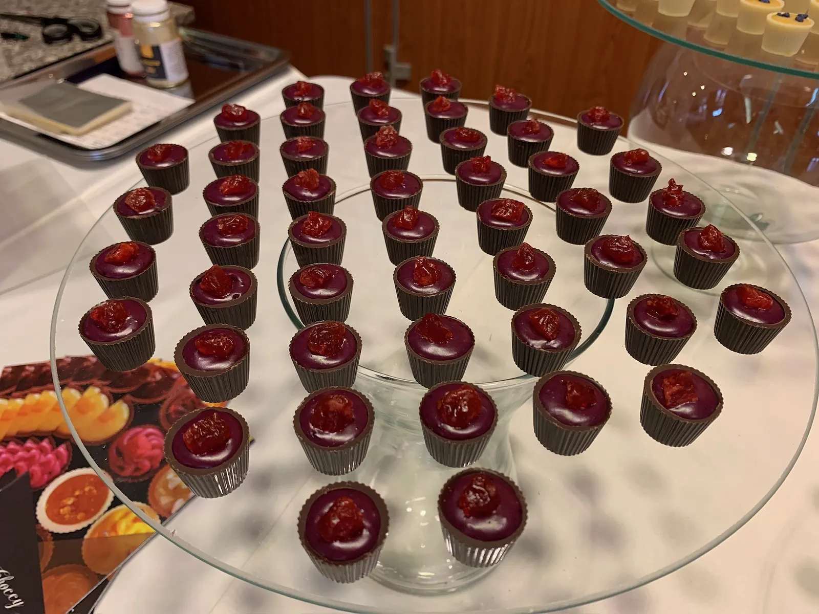 Filled chocolate cups on a glass stand on an event dessert table